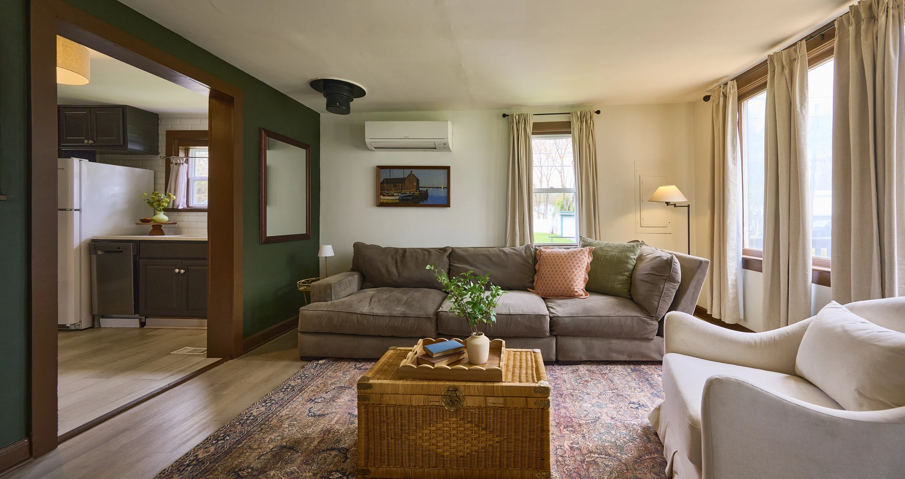 Living room at The Lakeside at Sylvan — cozy sectional sofa, green accent wall, and open kitchen view